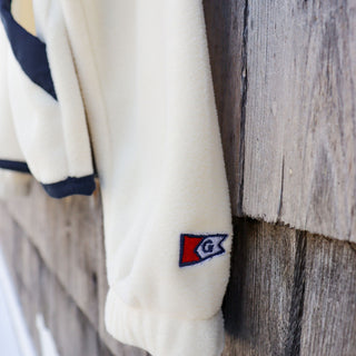 White sweater with a logo on a wooden surface